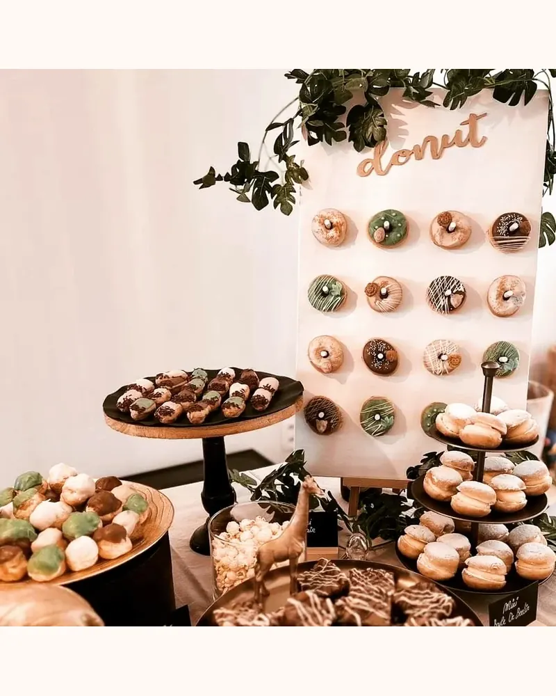 Donutwand met daarvoor schalen met cupcakes en gebakjes